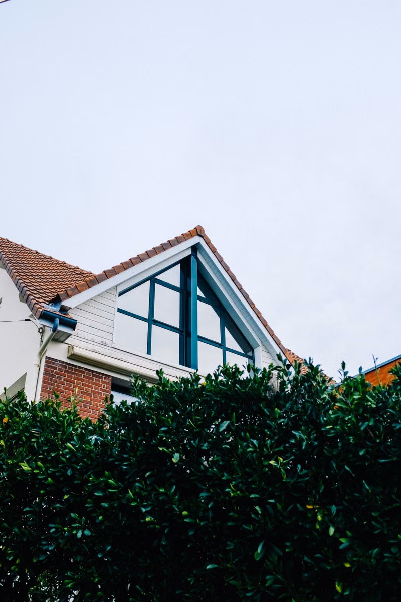 A gabled brick house surrounded by greenery